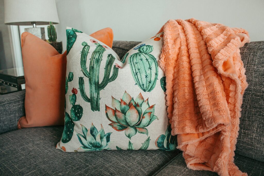 Elegant interior decor featuring cactus-themed pillows and a cozy blanket on a modern couch.